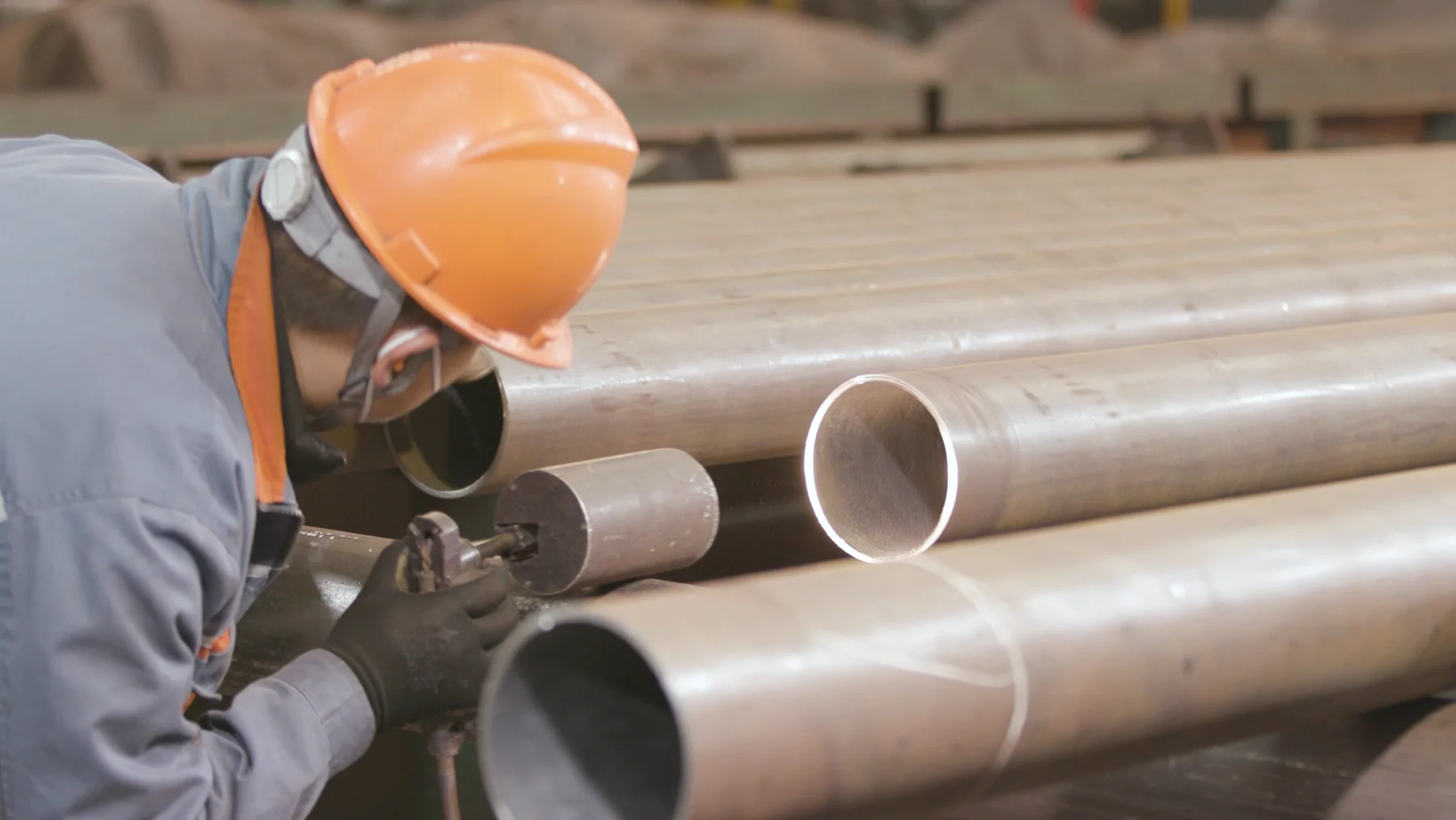 Worker grinding a steel pipe end