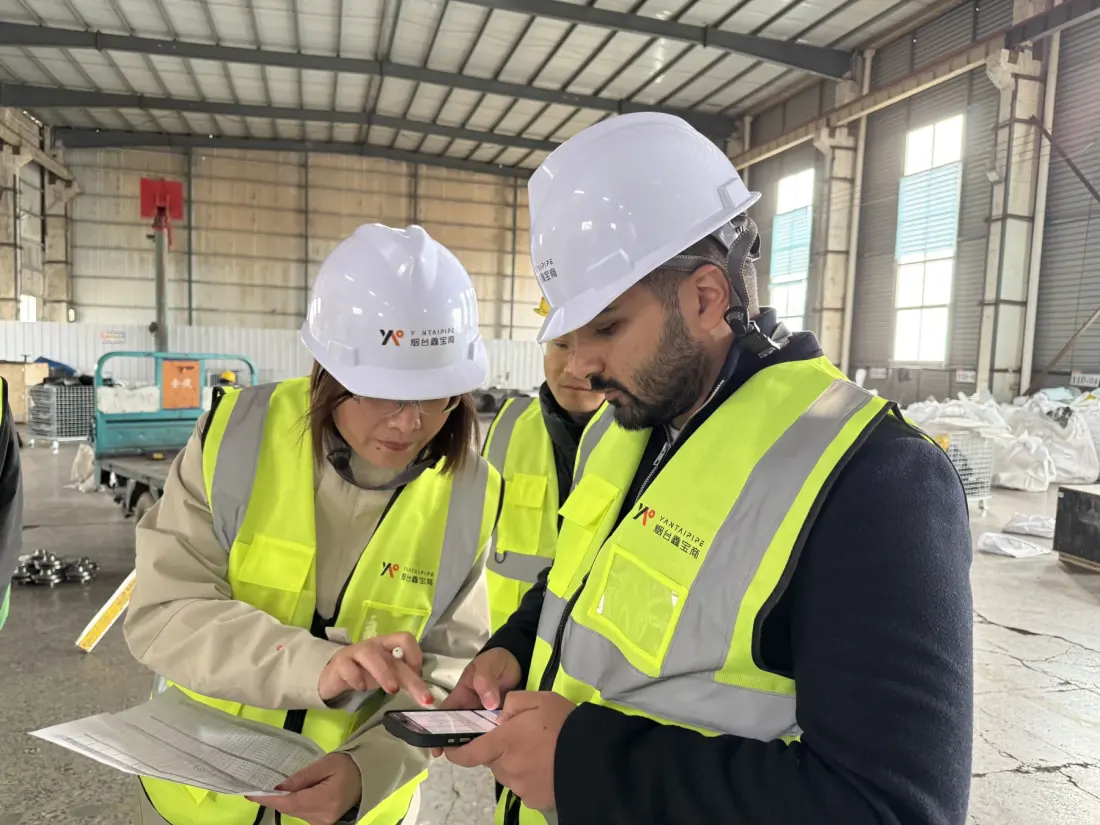 Third-party inspector reviewing pipe fittings documents in the factory