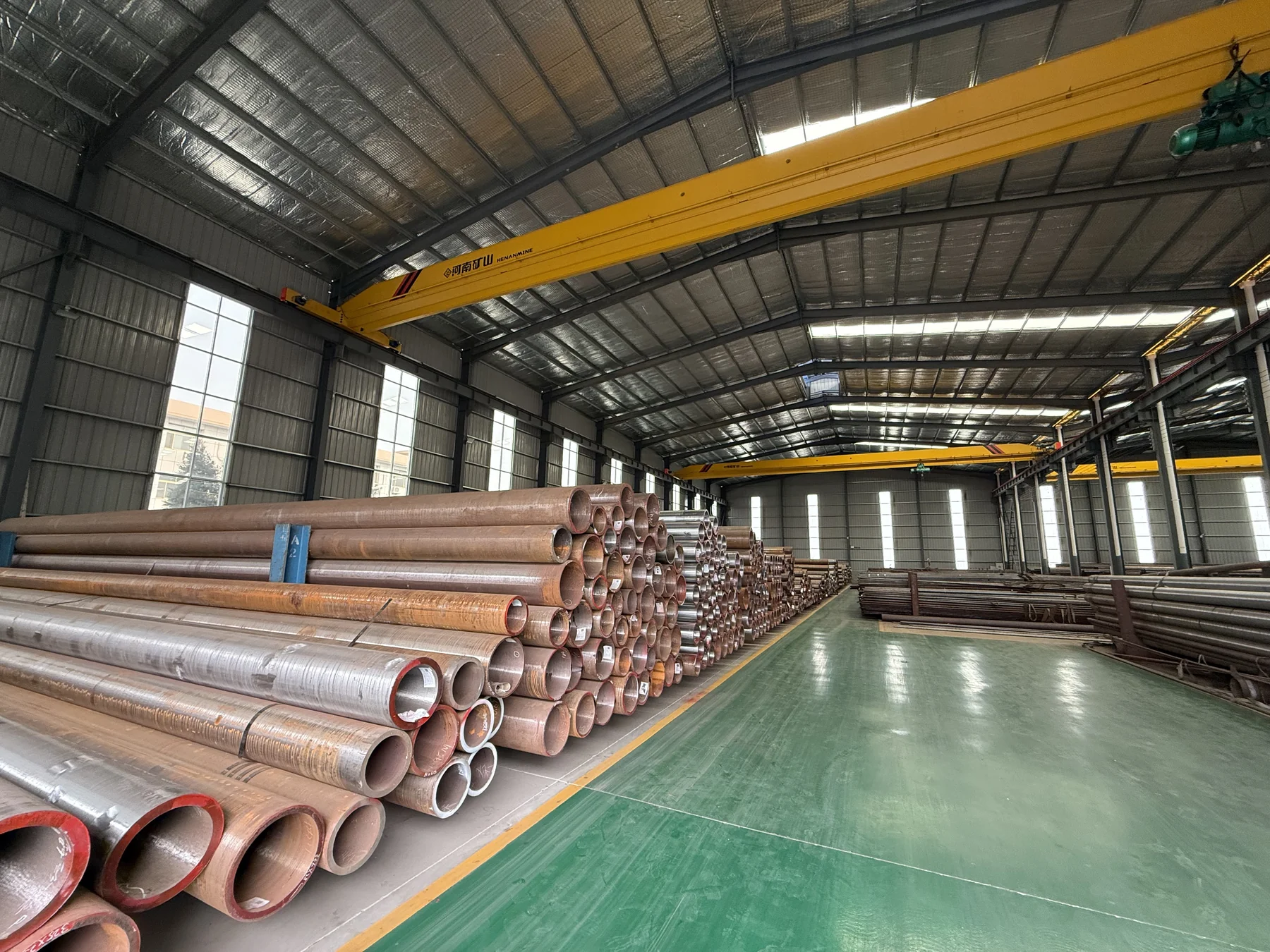 Stacked steel pipes beside the warehouse aisle